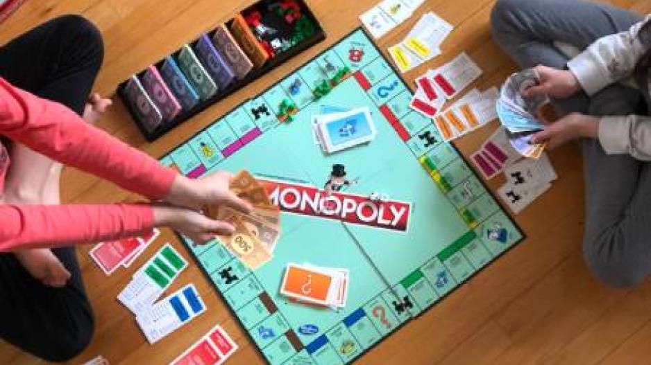 2 Spieler mit Spielgeld in den Händen spielen das Brettspiel Monopoly am Boden